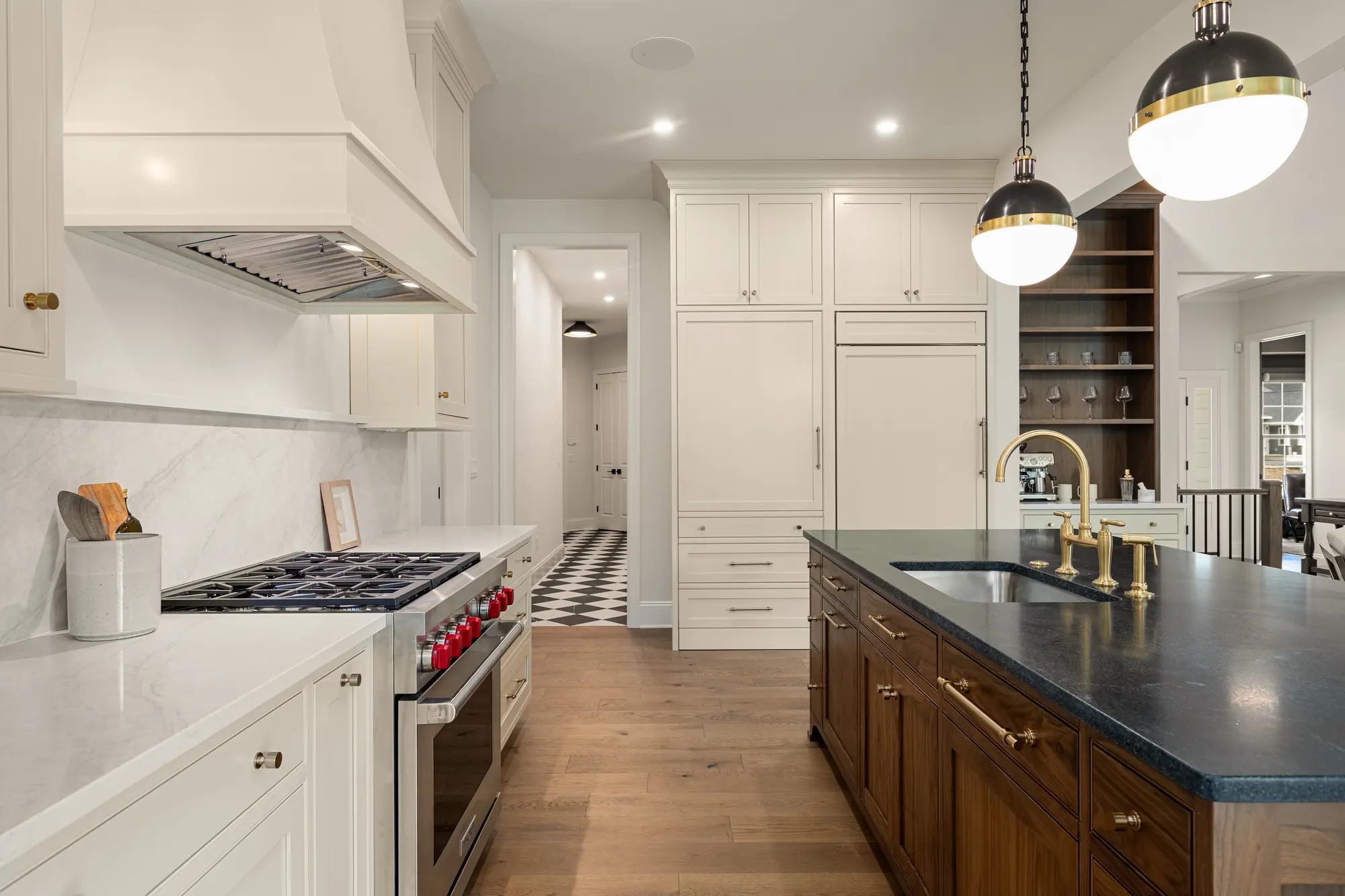 Kitchen in The Cabot Ridge with a range hood, white stone backsplash and a stained wood island