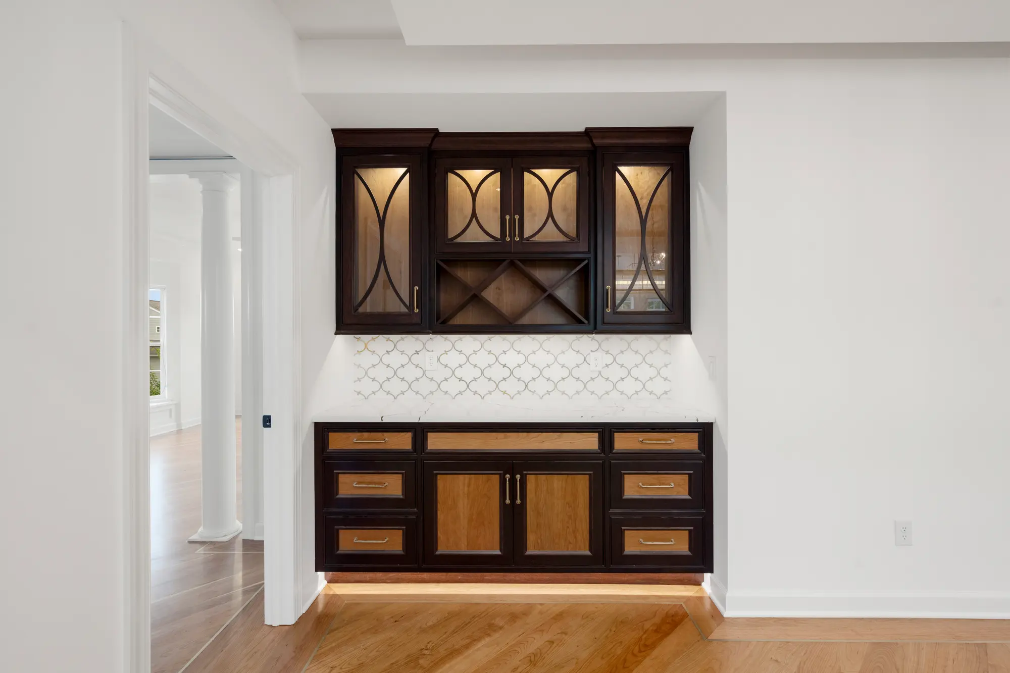 Built-in coffee bar with glass-front upper cabinets and a lit backsplash